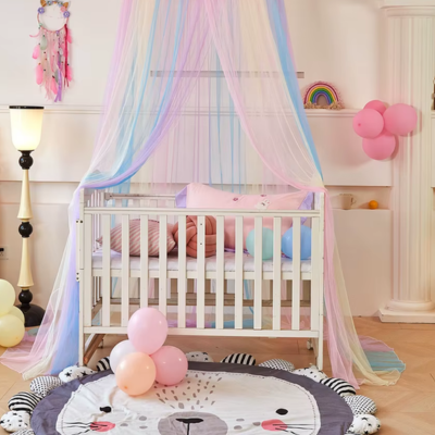 Un joli berceau blanc est décoré avec un ciel de lit bébé aux couleurs pastel, et d'une atmosphère douce et joyeuse.