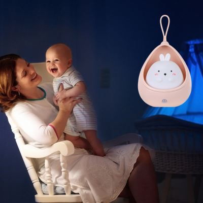 Maman Asie dans un fauteuil et bercement son enfant avec bébé veilleuse.