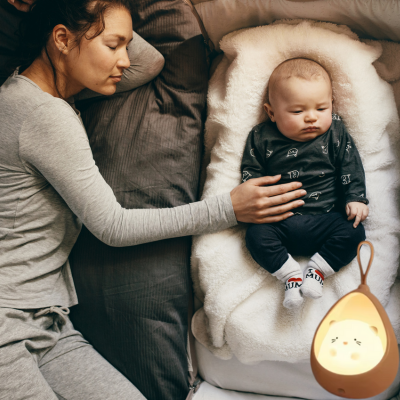 Maman est allongée à côté de son enfant, sa main posée sur lui avec tendresse veilleuse bébé diffuse une lumière enthousiasme.