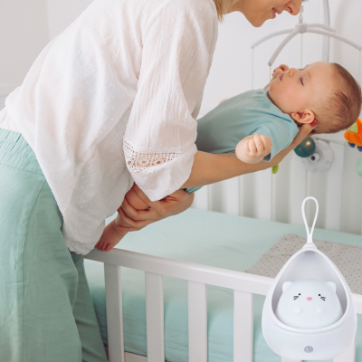 Doucement maman dépose son enfant dans berceau pour endormissement avec veilleuse bébé.