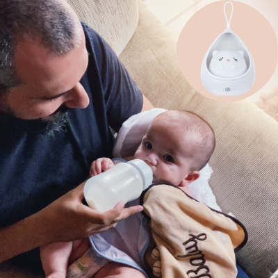 Papa est assis dans un fauteuil, c'est moment du biberon, accompagné de veilleuse bébé.