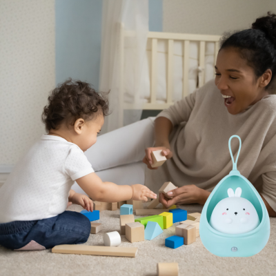 Maman joue avec son enfant empilant des blocs colorés elle pose à côté d'elle veilleuse bébé.