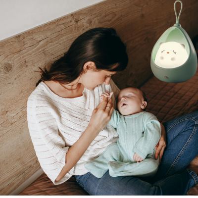 Maman est assise prend main avec tendresse de son enfant avec veilleuse bébé.